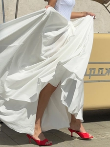 Dynamic view of an elegant white maxi skirt with wide hem and fluid drape on model