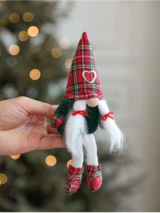 Detail of a handmade Christmas gnome plush with a heart patterned plaid hat and bokeh background