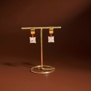 Vue détaillée des boucles d'oreilles dorées en acier avec pendentifs en zircone carrée