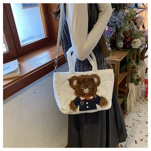 Detail of white quilted cotton handbag featuring a cute plush bear and detachable strap
