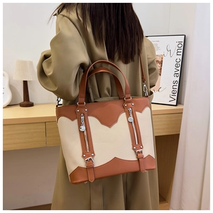 Detailed close-up of a vintage-style tote bag in beige and brown faux leather with strap detail
