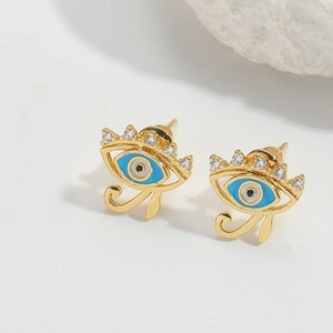 Macro shot of gold evil eye stud earrings with blue enamel and white zircon lashes