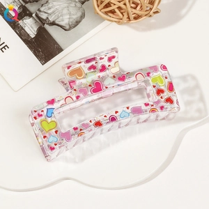 Detail of transparent hair claw clip with colorful heart patterns and LOVE text print