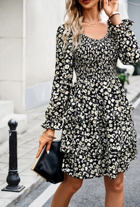 Detail view of long-sleeve floral dress with V-neck and pleated stitch design on a city street