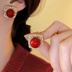 Close-up of vintage square earring with red gemstone and gold detailing on a model