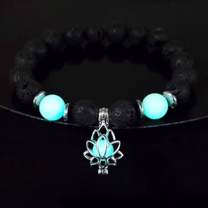 Macro view of luminous lotus charm bracelet with black lava rock and glowing turquoise beads