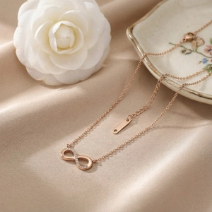 Close-up of 18k gold plated infinity necklace with small diamonds on soft beige silk