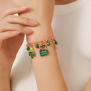 Close-up of a gold Christmas charm bracelet with festive tree and bell pendants on a wrist