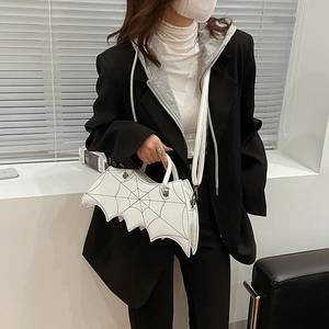 White bat-shaped PU handbag with black spider web embroidery held by a model in a blazer