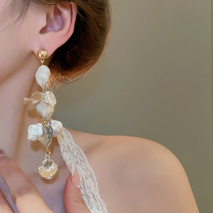 Close-up of model wearing long irregular shell tassel earrings with golden accents