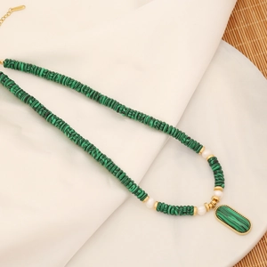 Detail of green malachite stone necklace with white pearls and gold accents on marble tray