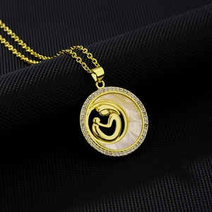 Macro detail of gold-tone necklace featuring mother and child embrace on shell pendant