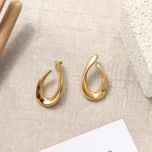 Exaggerated gold irregular C-shape teardrop earrings on minimalist aesthetic background