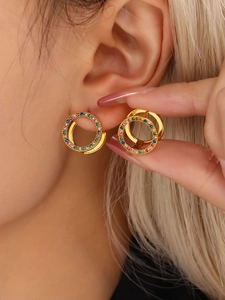 Primer plano de pendientes de aro dorados con circonitas de colores en una modelo