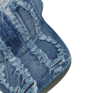 Close-up of distressed denim baseball cap detailing washed fabric and frayed edges