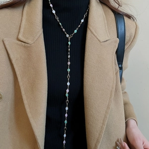 Detail of a long Y-shaped golden necklace with colorful resin gemstones on model