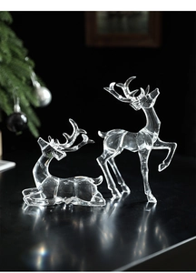 Macro shot of two transparent acrylic Christmas reindeer with faceted crystal-like finish