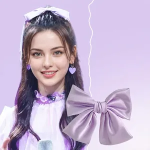 Detail view of large purple satin bow hair clip showing silk luster and clip mechanism