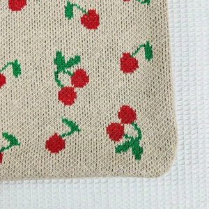 Detailed close-up of knitted tote bag featuring red and green cherry patterns