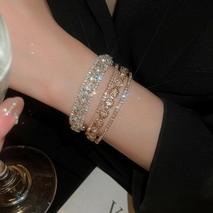 Close-up of stacked triple-layer bracelets featuring brilliant zircon stones in silver and rose gold
