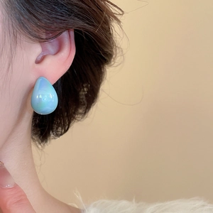 Close-up of light blue teardrop earring with aurora pearl finish on female ear