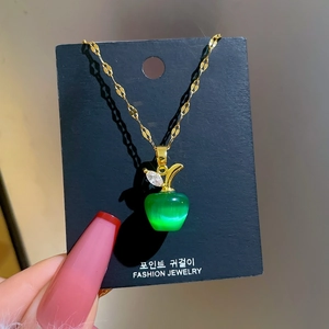 Detail of apple pendant with cat's eye stone, gold leaf with zircon, and ripple chain