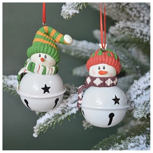 Detail of snowman metal bell ornament with knitted hats on a snowy Christmas tree