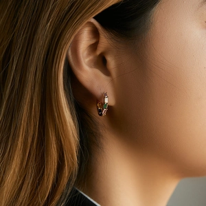Close-up of gold hoop earrings with multi-color zircons worn by a model for a luxury look