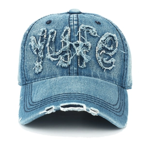Détail de casquette vintage avec écusson brodé et texture denim délavé effet usé