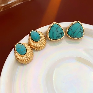 Vintage geometric gold-plated earrings set with green turquoise stones on ceramic plate