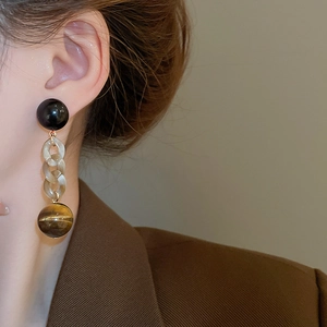 Detail of vintage long drop earrings with amber beads and tiger eye stone ball on a model