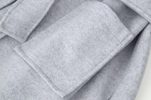 Détail d'un manteau en laine gris montrant les coutures de la poche et la texture