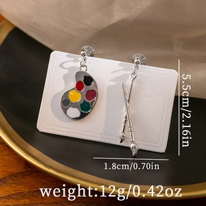 Macro view of paintbrush and palette earrings with detailed dimensions and weight info