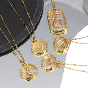 Detail of five gold pendants featuring moon star and heart shapes with glitter resin