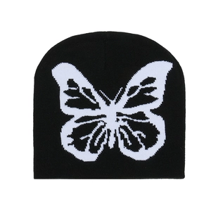 Détail de la texture tricotée et du motif papillon blanc sur ce bonnet noir d'hiver