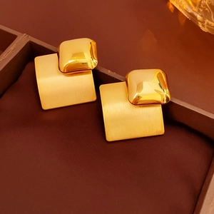 Macro detail of gold-plated geometric diamond earrings with brushed and polished textures
