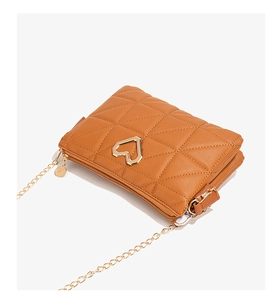 Detail of tan quilted square crossbody bag with gold heart clasp and chain strap