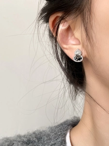 Close-up of elegant silver gourd stud earrings with black and white zircon crystals