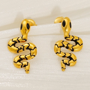 Close-up of golden snake-shaped earrings with black texture on white fabric