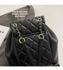 Close-up of diamond quilted texture and golden chain strap on a black backpack