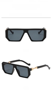 Detail view of black square sunglasses with golden metal hinges and gray lenses