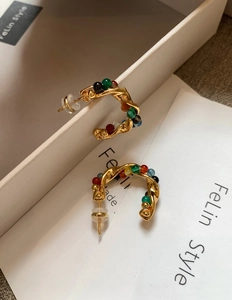 Detail of gold spiral earrings with multicolored beads and secure silicone backings