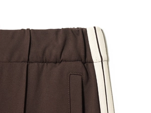 Detail of elastic waistband and white side stripes on dark brown retro sports trousers