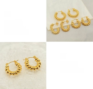 Macro detail of polished gold croissant twist earrings with high-gloss plated texture