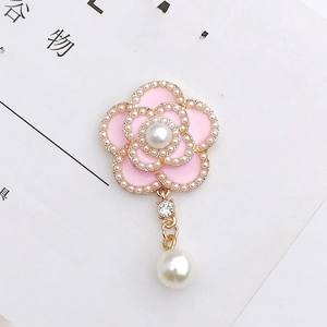 Detailed macro shot of pink camellia pendant with pearls and gold alloy finish