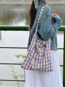Detailed view of pink and blue plaid canvas tote bag with side label on shoulder strap