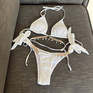 Macro shot of white ribbed bikini featuring gold chain belt with sea shell and starfish charms