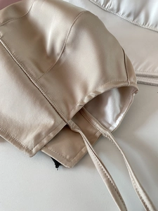 Detail of champagne satin vintage bonnet featuring smooth texture and fine stitching lines