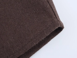 Macro shot of dark brown linen knit fabric showing dense texture and hem stitching details