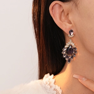 Detailed view of vintage gold earrings with purple teardrop crystals and zircons